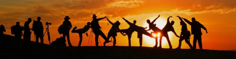Eine Gruppe von Menschen tanzt vor dem Sonnenuntergang